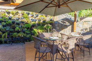 Un patio con mobiliario de mimbre y un muro de piedra con plantas en macetas.