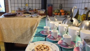 Een ontbijttafel met diverse etenswaren, kopjes en een waterkoker.