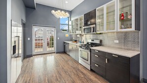 Une cuisine moderne avec des meubles de couleur sombre, une cuisinière en acier inoxydable et un meuble supérieur avec une porte en verre.