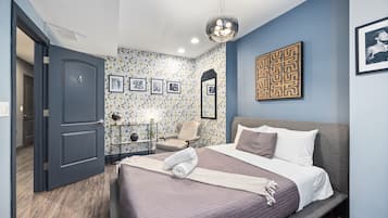 A bedroom with a bed, a chair, a desk, and a door.