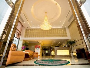 Un vestíbulo de hotel con mostrador de recepción, zona de estar y un candelabro.