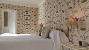 Une chambre à coucher avec un lit, une table de chevet avec une lampe et un papier peint à motifs floraux.