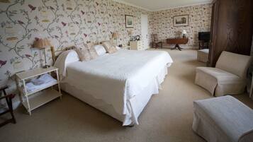 A bedroom with a large bed, a bedside table, a chair, a dresser, and a television.