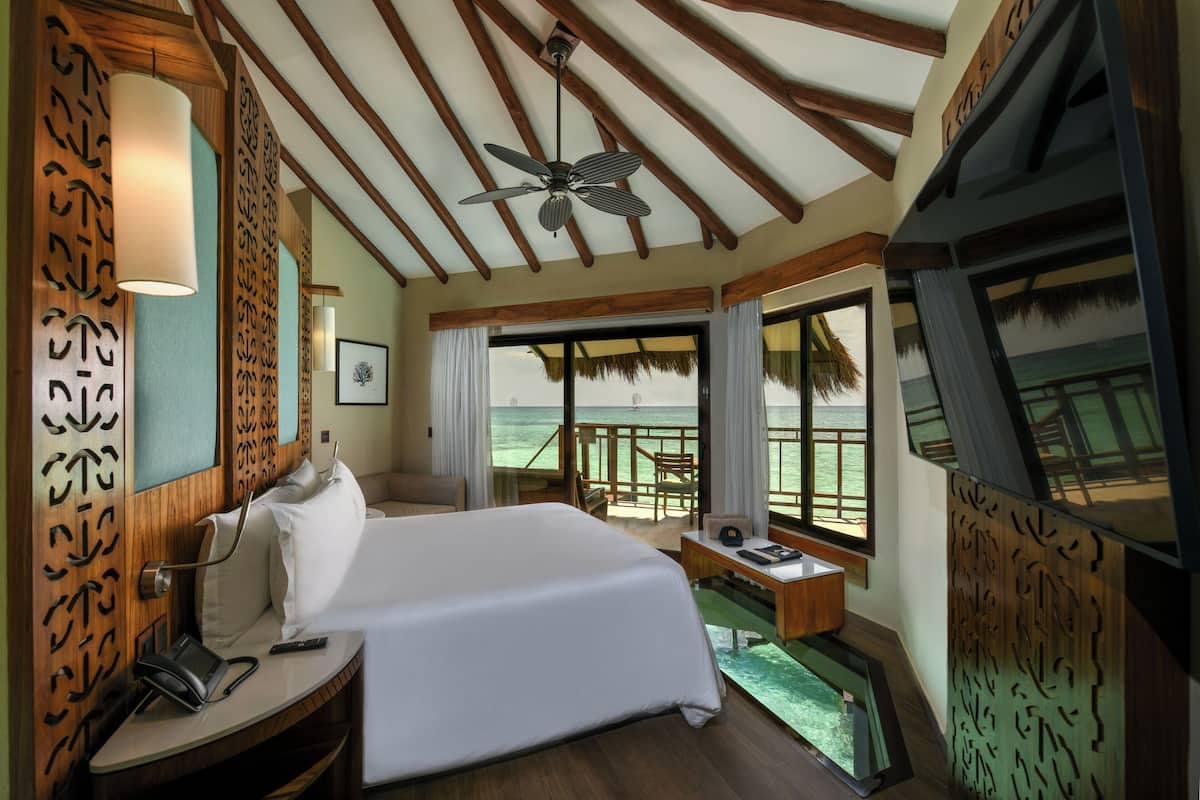 Ein Hotelzimmer mit Bett, Schreibtisch und großen Fenstern mit Blick aufs Meer.