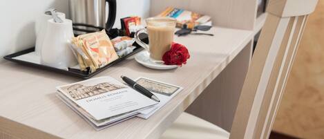 Una preparación para el desayuno con una cafetera, una bandeja con tazas de café, una rosa y algunos alimentos para el desayuno sobre una mesa de madera.