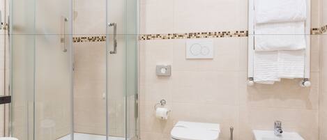 A modern bathroom with a glass shower enclosure, a toilet, a bidet, and a sink.