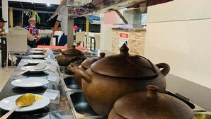 A buffet setup with multiple serving stations, including large ceramic pots and plates with utensils. - Hotel Dama Business Center (São Gonçalo do Amarante)
