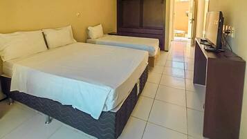 Een hotelkamer met twee bedden, een kledingkast, een televisie en een betegelde vloer.