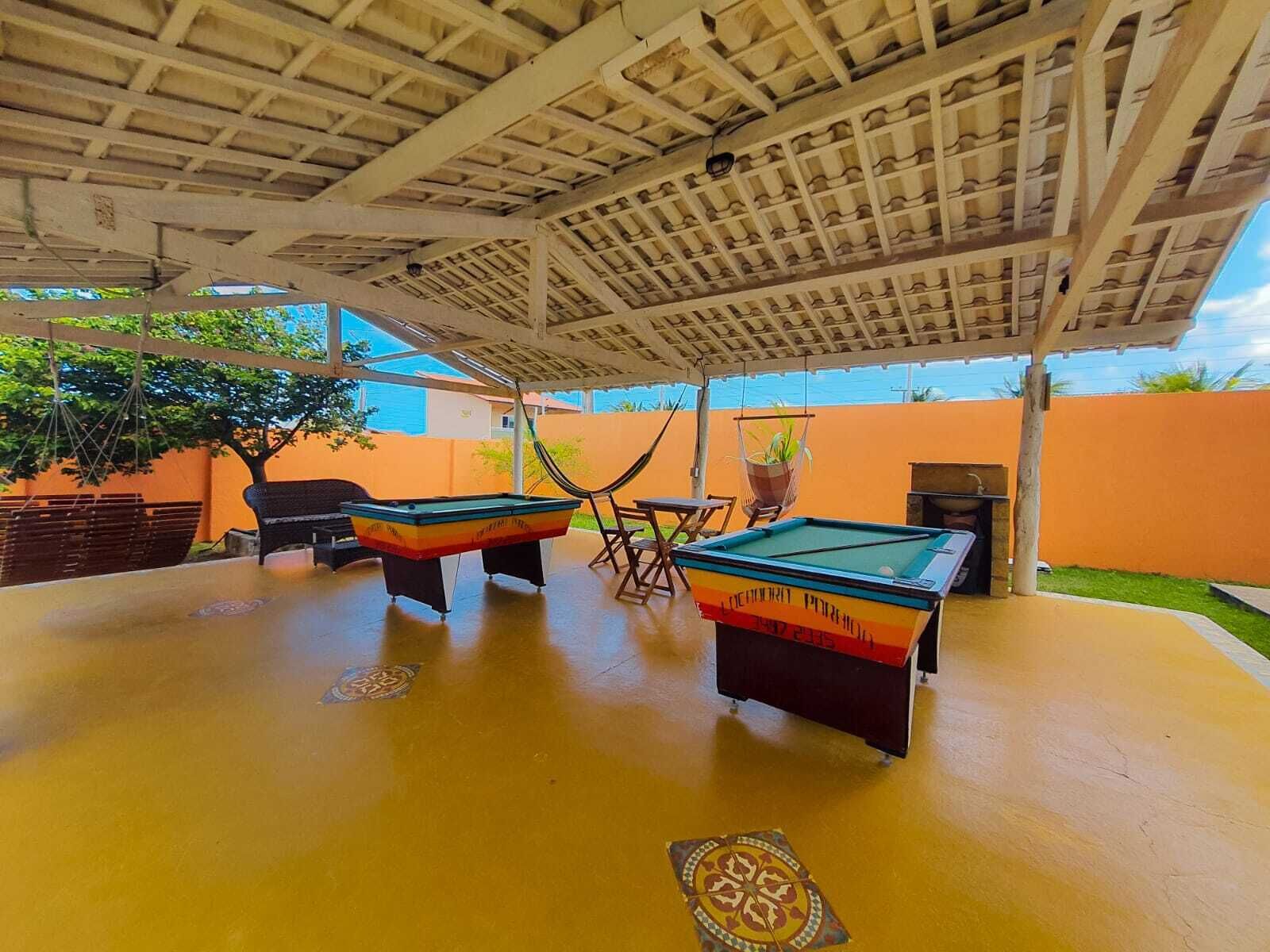 Un área de piscina exterior con dos mesas de billar, una hamaca y una parrilla.