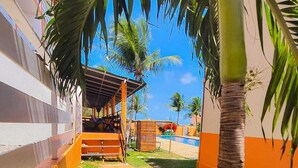 A courtyard with a pool, palm trees, and a covered seating area. - Hotel Dama Business Center (São Gonçalo do Amarante)