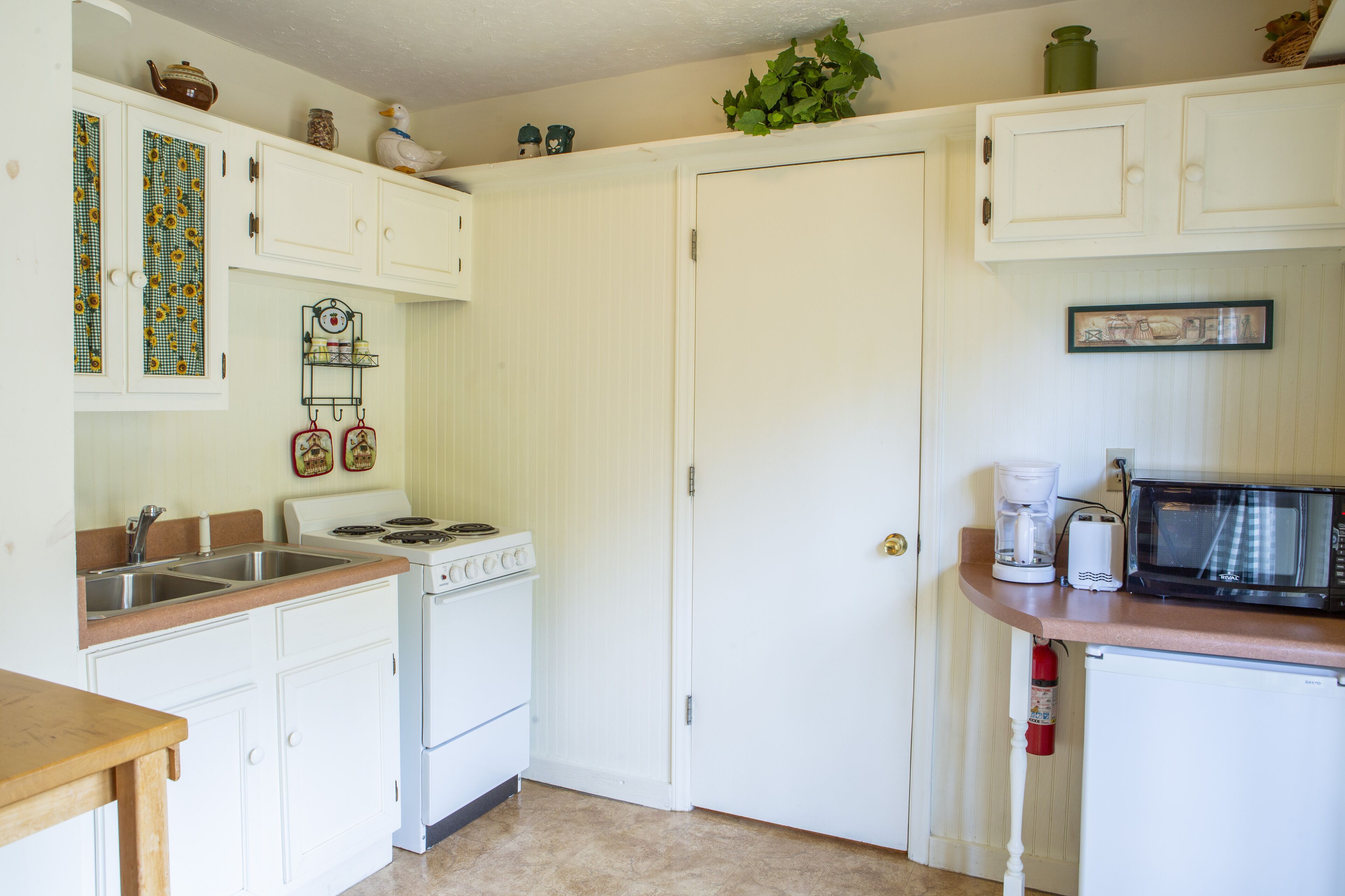 A kitchen with white cabinets, a stove, a microwave, and a sink.