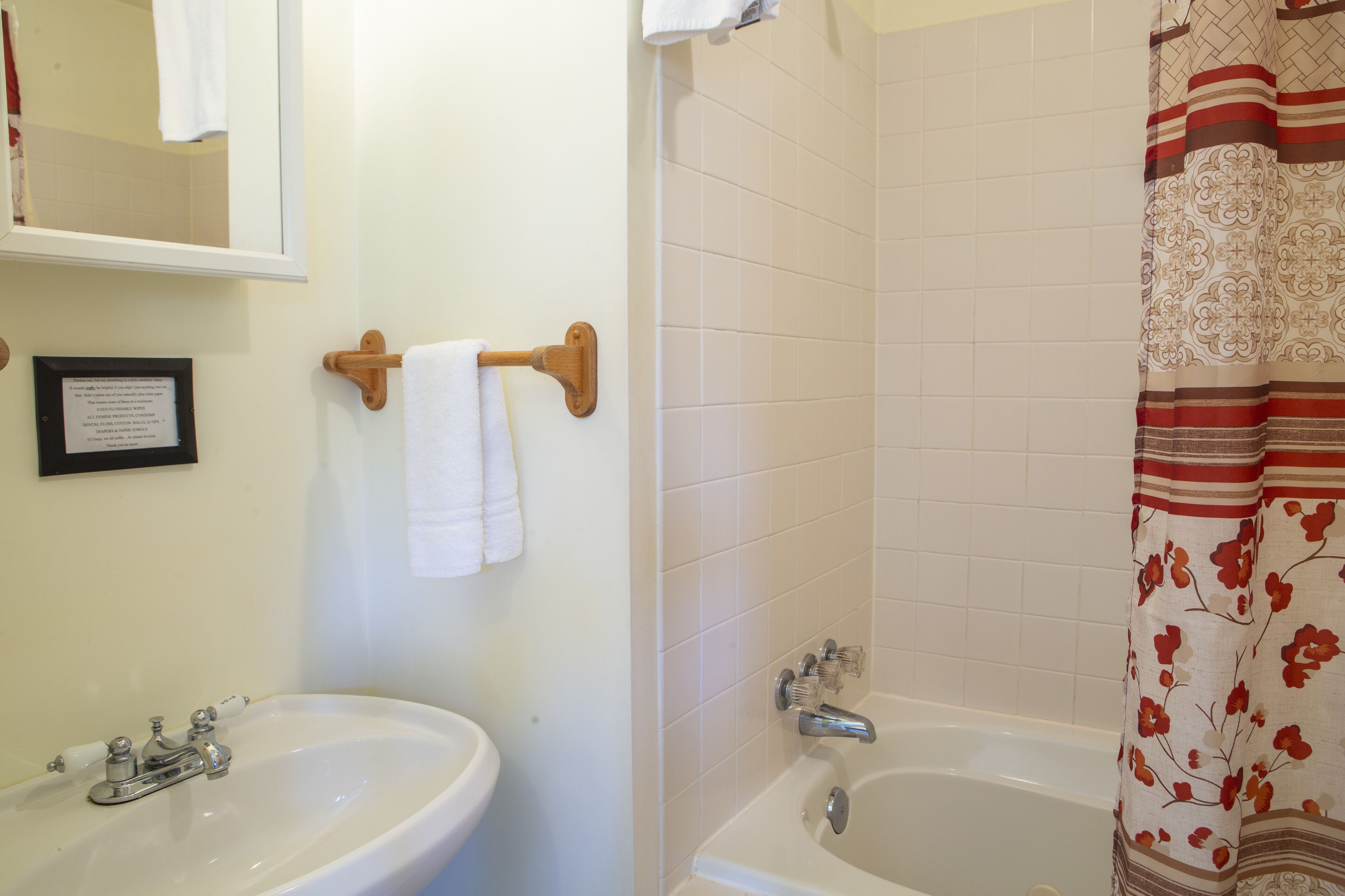 A bathroom with a sink, mirror, and bathtub.
