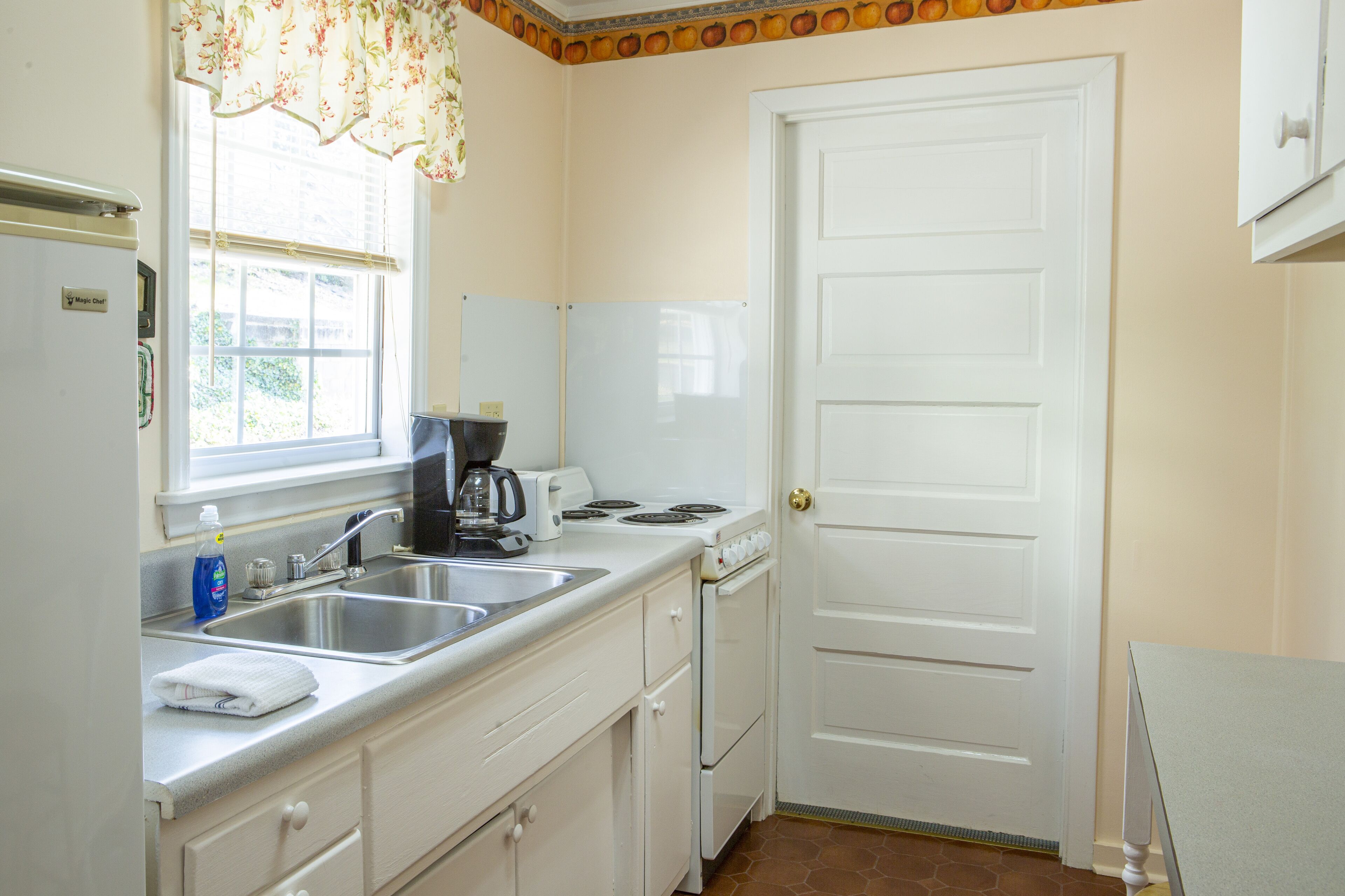 A kitchen with a double sink, a stove, and a refrigerator.