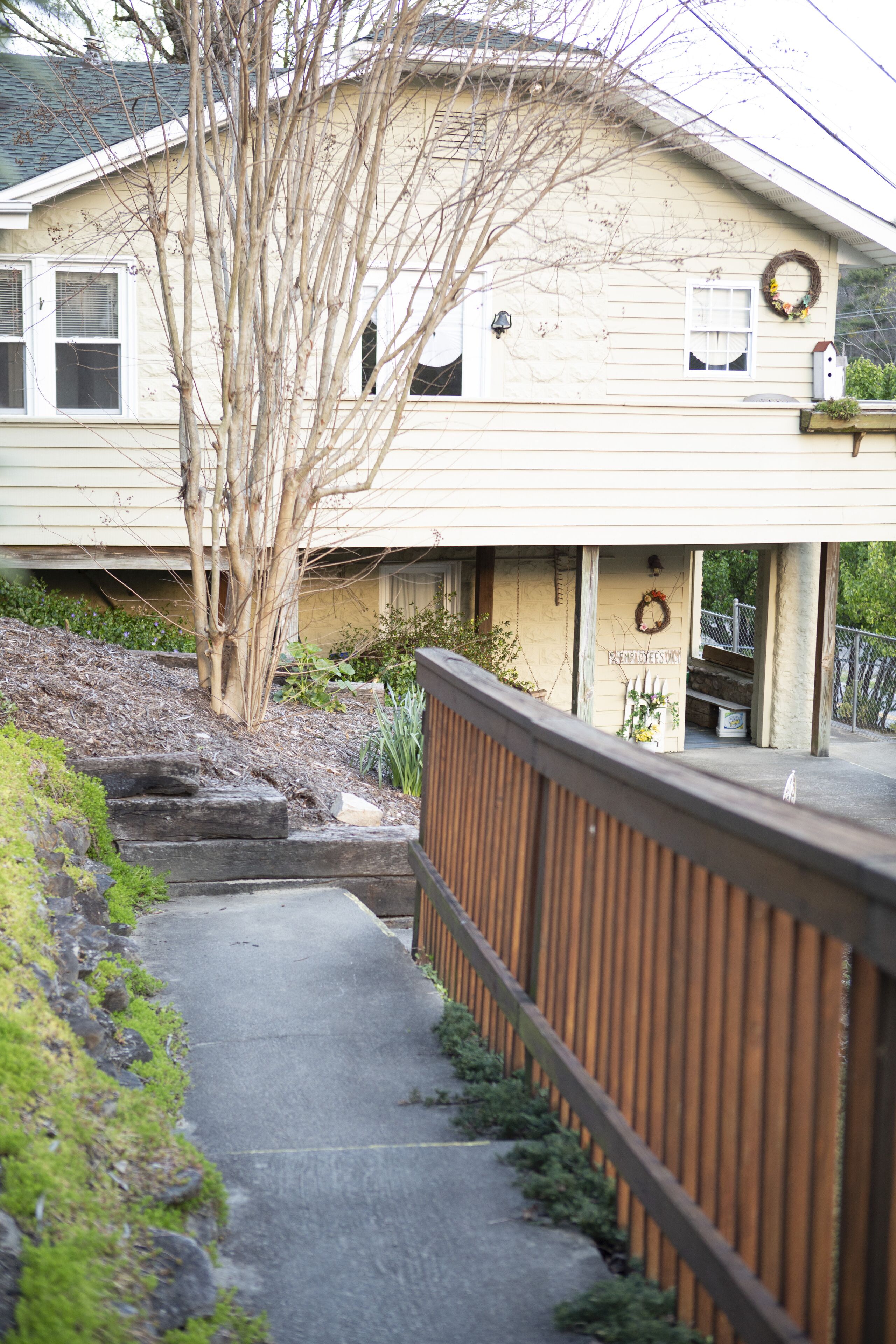A house with a porch, a wooden fence, and a pathway leading to the entrance.