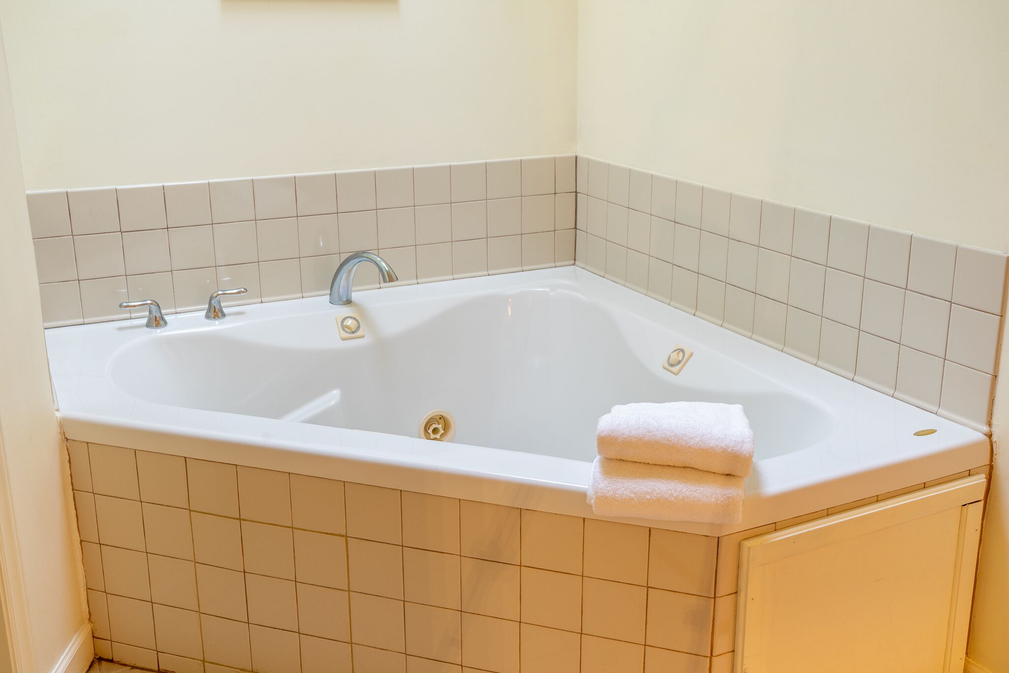 Una vasca da bagno rettangolare con due rubinetti, uno scarico e un asciugamano sul bordo.
