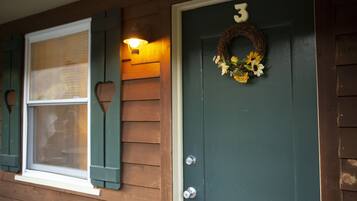 A house with a green door, a number '3' above the door, a wreath with flowers, and a window with shutters.