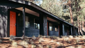Situated in a wooded area, this single-story building features large windows and dark wood panels.
