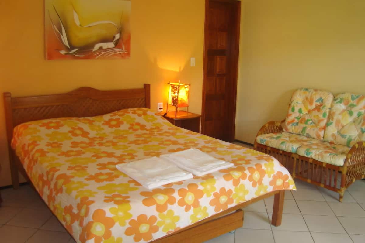 Ein Hotelzimmer mit Bett, Sessel, Lampe und Tür.