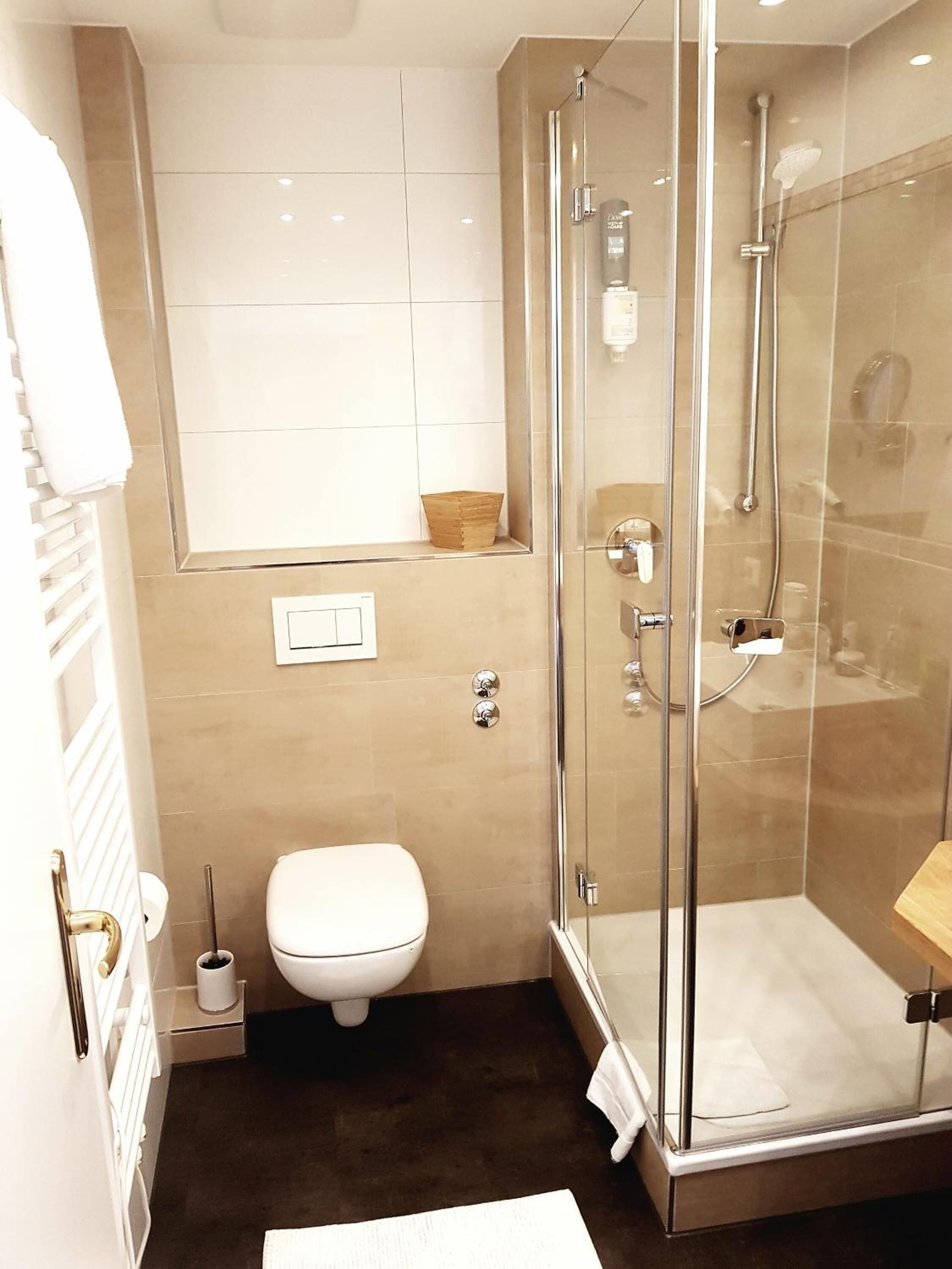 A modern bathroom with a glass-enclosed shower, a toilet, and a sink.