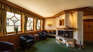 A cozy living room with a fireplace, comfortable seating, and large windows with curtains. - Hotel Württemberger Hof (Reutlingen)