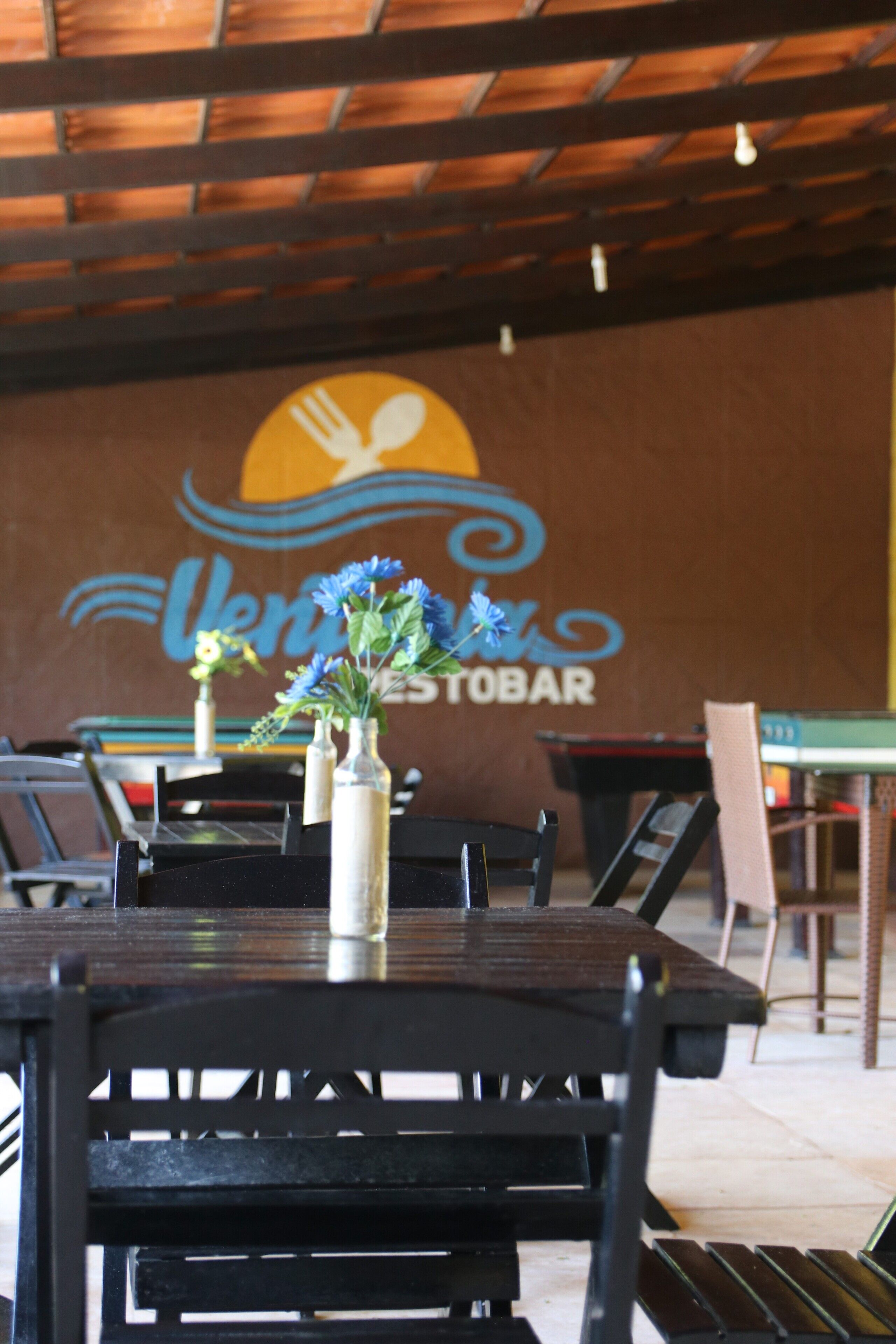 A restaurant interior with tables, chairs, and a wall with a logo.
