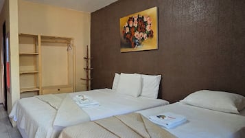 Habitación de hotel con dos camas, un armario, un cuadro y una lámpara en el techo.