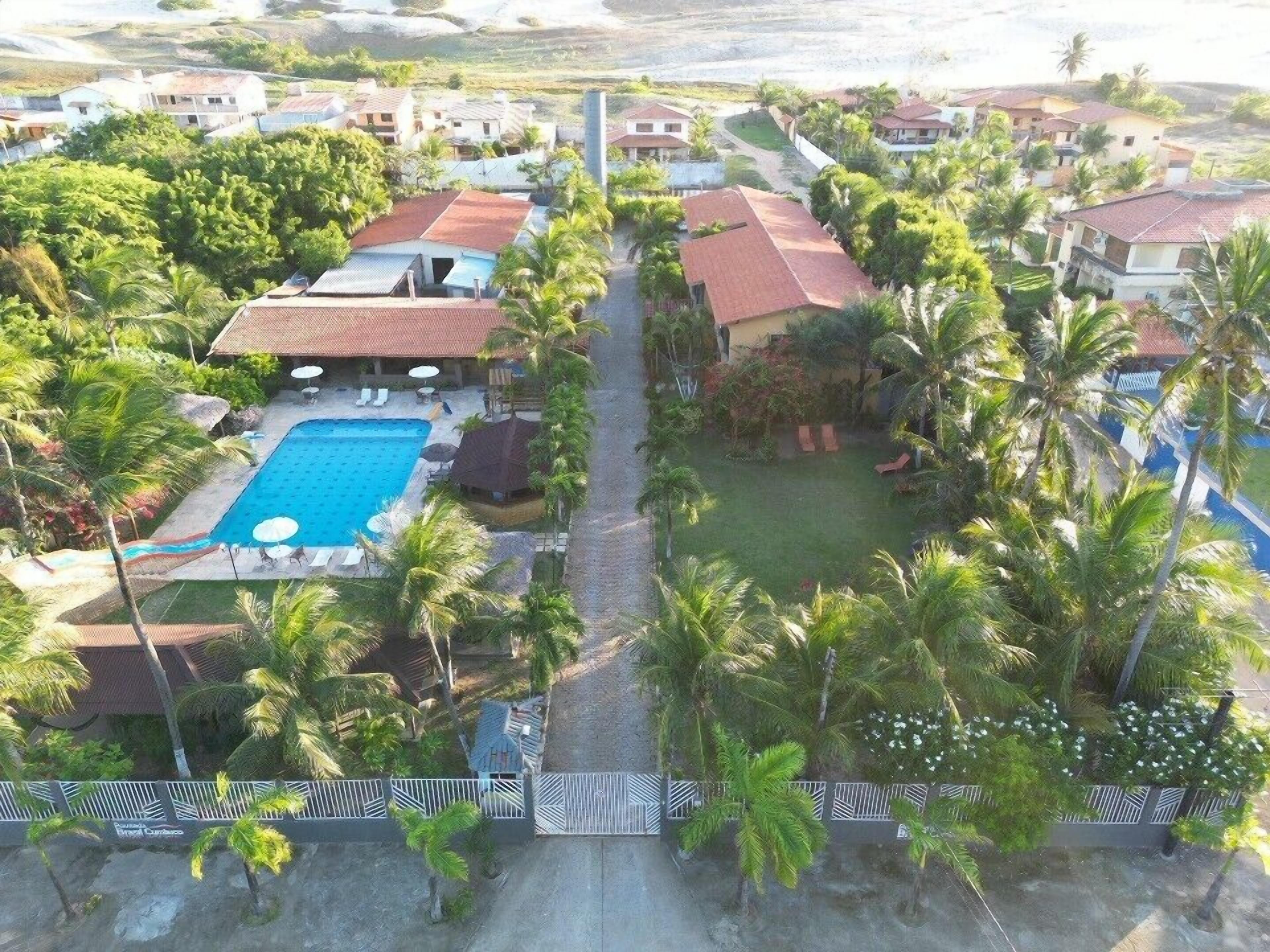 A resort with a swimming pool, palm trees, and a paved walkway.