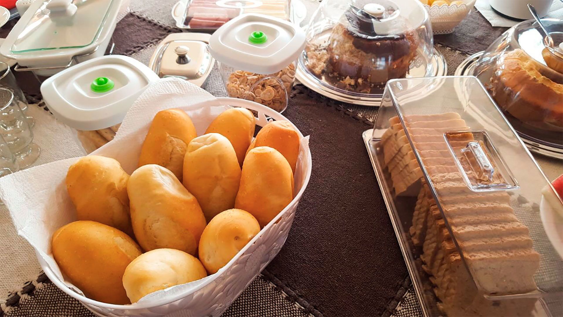 A table with various food items including bread rolls, a cake, and other pastries.