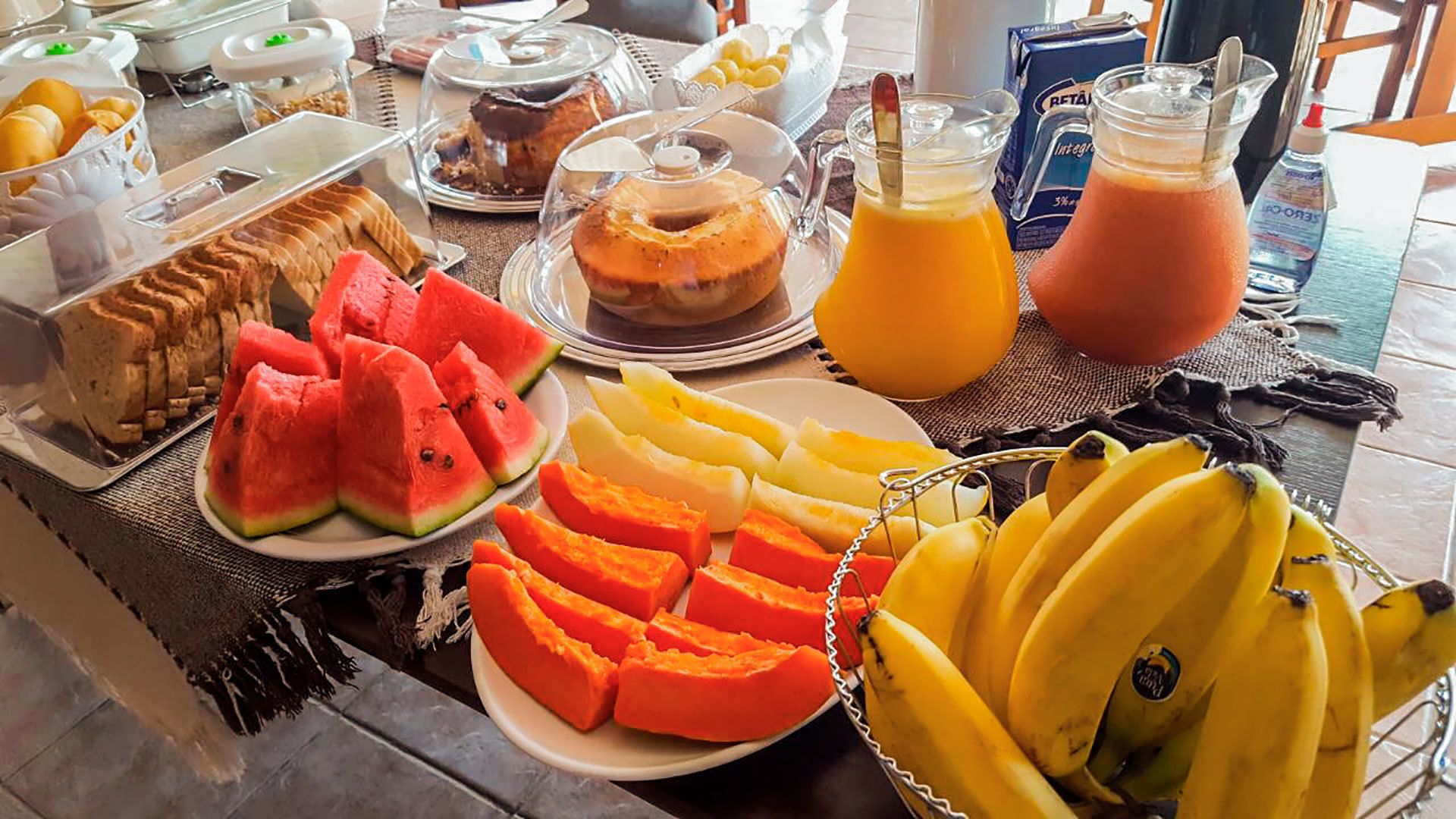 Un bufé de desayuno con diversas frutas, bollería y bebidas.