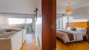 A modern bedroom with a wooden headboard, a large bed, and a view of the outdoors through a sliding glass door. - Lymack Suites (Nairobi)