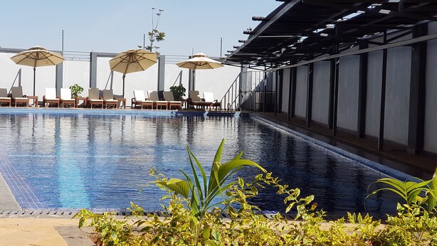 A swimming pool with lounge chairs and umbrellas, surrounded by plants. - Lymack Suites (Nairobi)