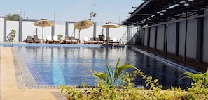 A swimming pool with lounge chairs and umbrellas, surrounded by plants. - Lymack Suites (Nairobi)