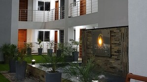 A multi-story building with balconies, a reception area, and a small outdoor garden with benches. - Lymack Suites (Nairobi)