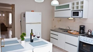 Una cocina moderna con armarios blancos, un microondas integrado, una cocina a gas y un comedor con mesa y sillas.