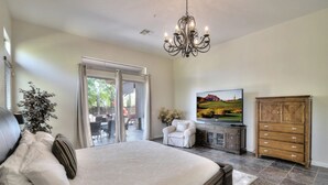 A bedroom with a large bed, a TV, a wooden cabinet, and a sliding glass door leading to an outdoor area. - Vista Bonita (Scottsdale)