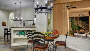 A dining area with a chandelier, a dining table with chairs, and a view of a staircase leading to a balcony. - Vista Bonita (Scottsdale)