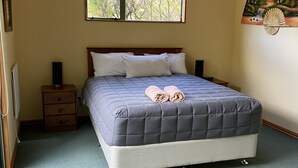Une chambre à coucher avec un grand lit, une table de chevet, une commode, une fenêtre et un élément décoratif mural.