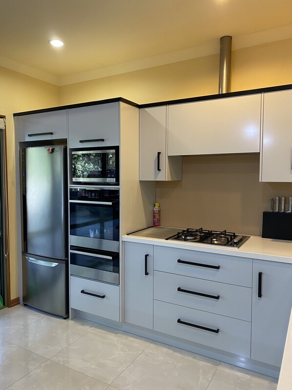 A modern kitchen with stainless steel appliances, white cabinetry, and a gas stove.
