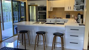 Une cuisine moderne dotée d’un îlot central, d’appareils électroménagers en acier inoxydable et d’une grande fenêtre.