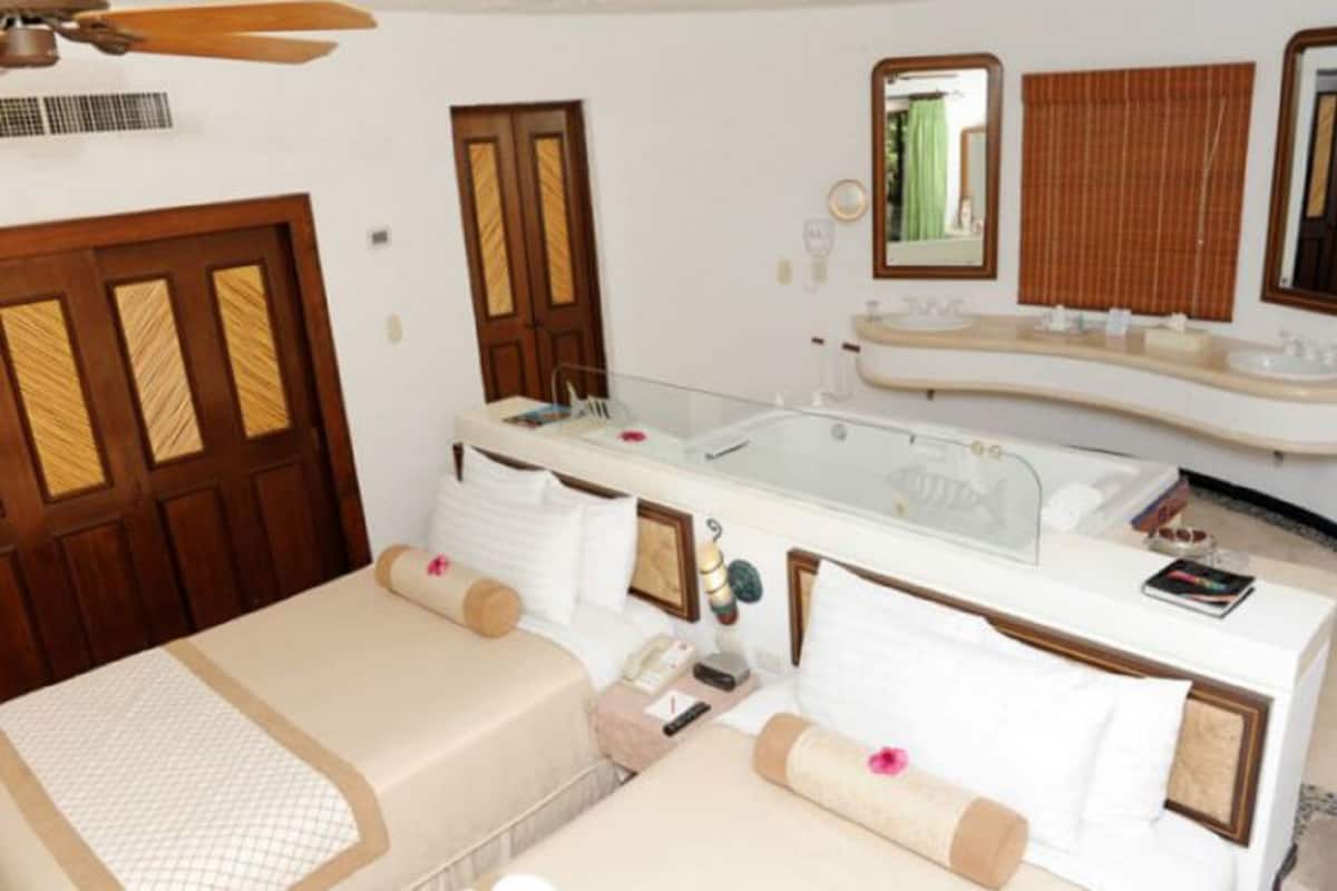 Ein Hotelzimmer mit Bett, Badezimmer mit großem Spiegel, Waschbecken und Deckenventilator.