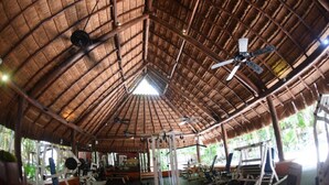 A gym with a thatched roof and ceiling fans. - Bel Air Collection Resort & Spa Riviera Maya - All Inclusive (Xpu-Ha)