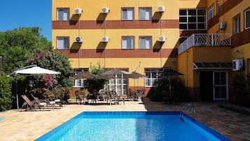 Una piscina al aire libre, sombrillas, tumbonas