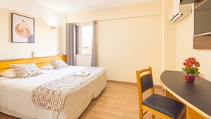 A hotel room with a bed, a desk, a chair, a TV, and a window with curtains. - Itapetinga Hotel (Atibaia)