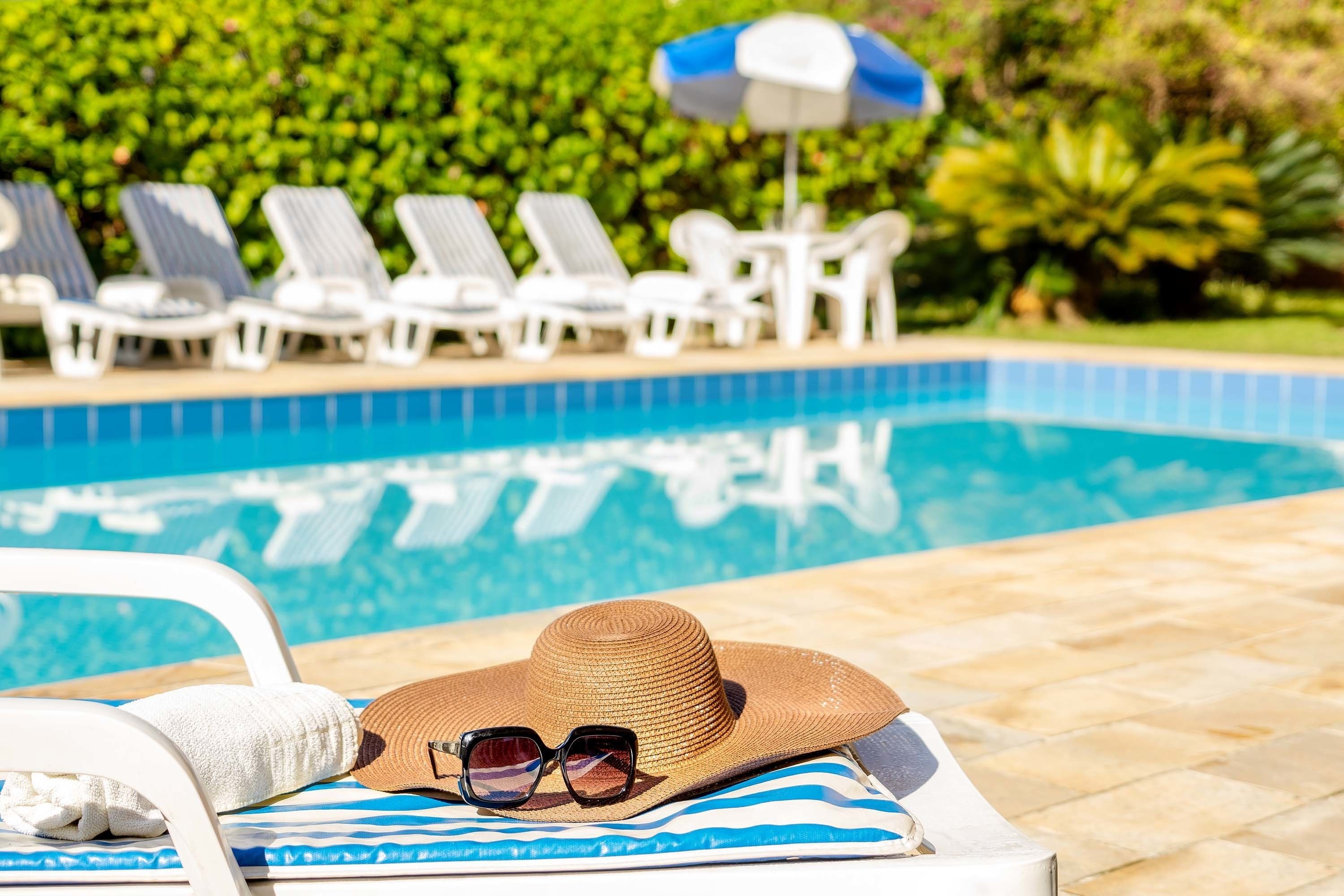 Una piscina al aire libre, sombrillas, sillones reclinables de piscina