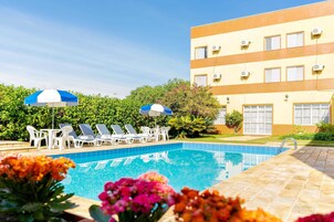 Una piscina al aire libre, sombrillas, sillones reclinables de piscina