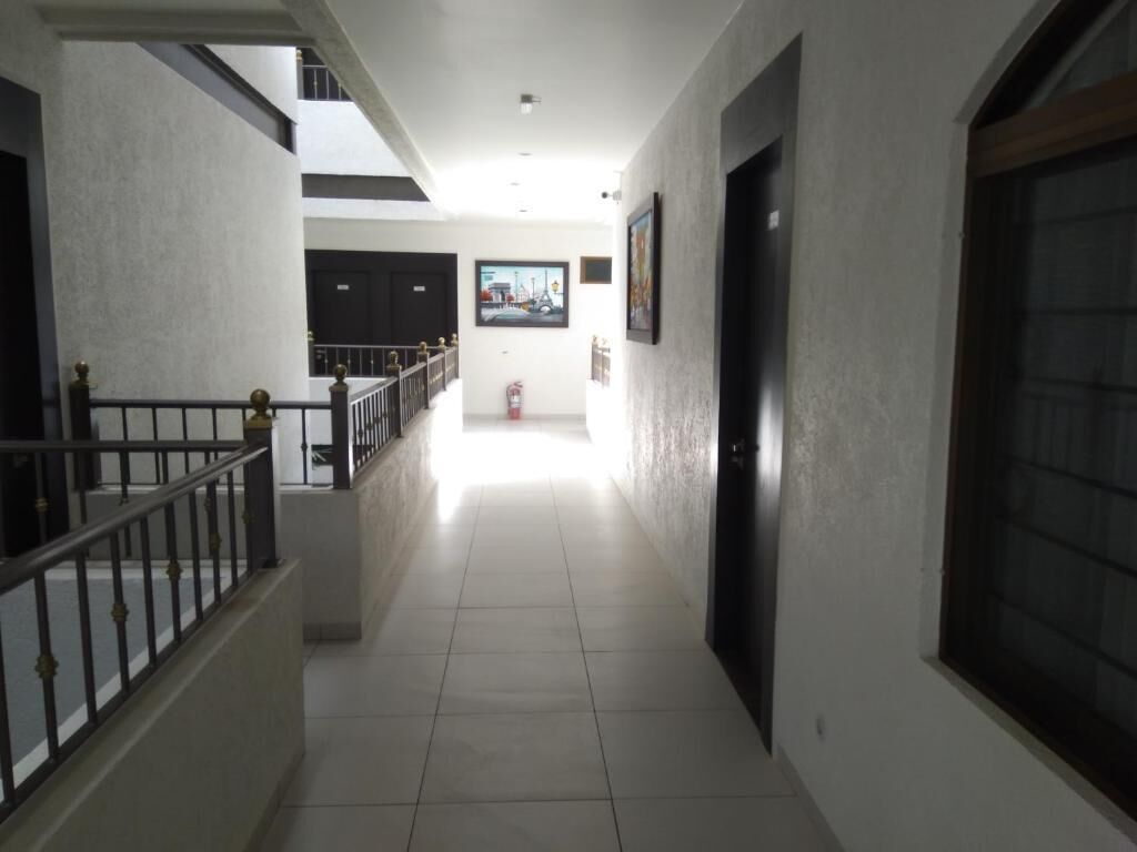 Un pasillo con una escalera a la izquierda, una puerta a la derecha y un cuadro en la pared.