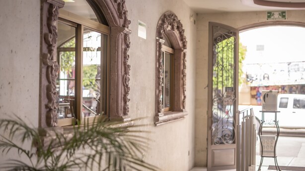 A hallway with ornate architectural details, a potted plant, and a sign indicating an exit.