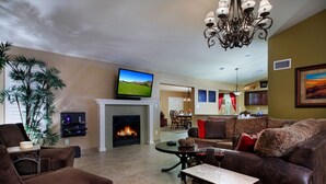 A living room with a fireplace, television, and seating area. - Windrose (Scottsdale)