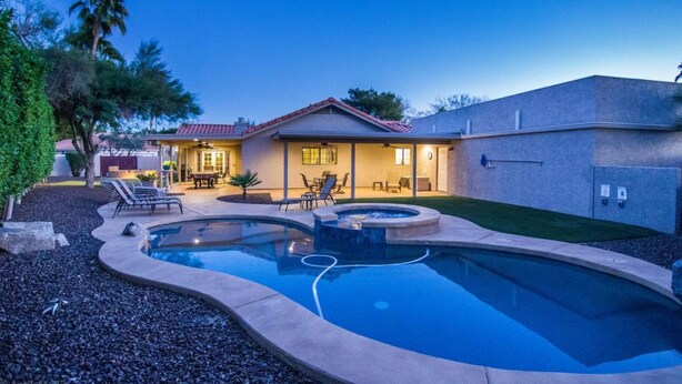 A residential property with a swimming pool, patio furniture, and a covered outdoor seating area. - Windrose (Scottsdale)