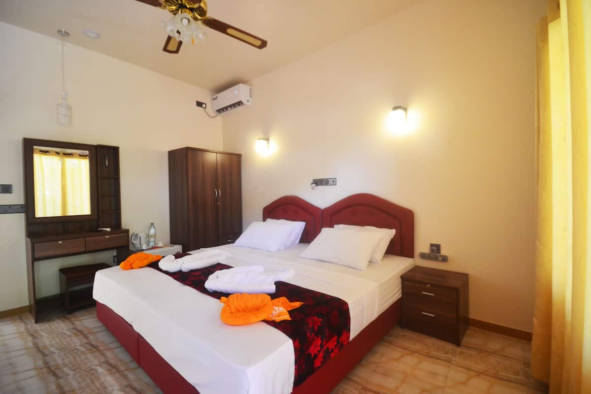A neatly made bed with white and red bedding, a wooden headboard, and a bedside table with a lamp.